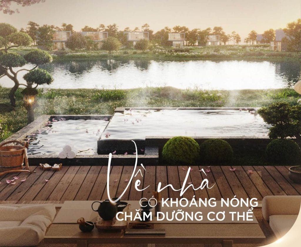 Hình ảnh một khu vực thư giãn ngoài trời tại Alluvia City với bể khoáng nóng, bao quanh bởi cây xanh và hồ nước yên bình. Sàn gỗ được trang trí với bộ bàn trà và ghế sofa, tạo không gian ấm cúng. Chữ "VỀ NHÀ CÓ KHOÁNG NÓNG CHĂM DƯỠNG CƠ THỂ" được in nổi bật, nhấn mạnh giá trị của khoáng nóng tự nhiên tại dự án.